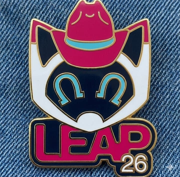 Enamel pin of a cowboy-hat cat with the LEAP 26 logo