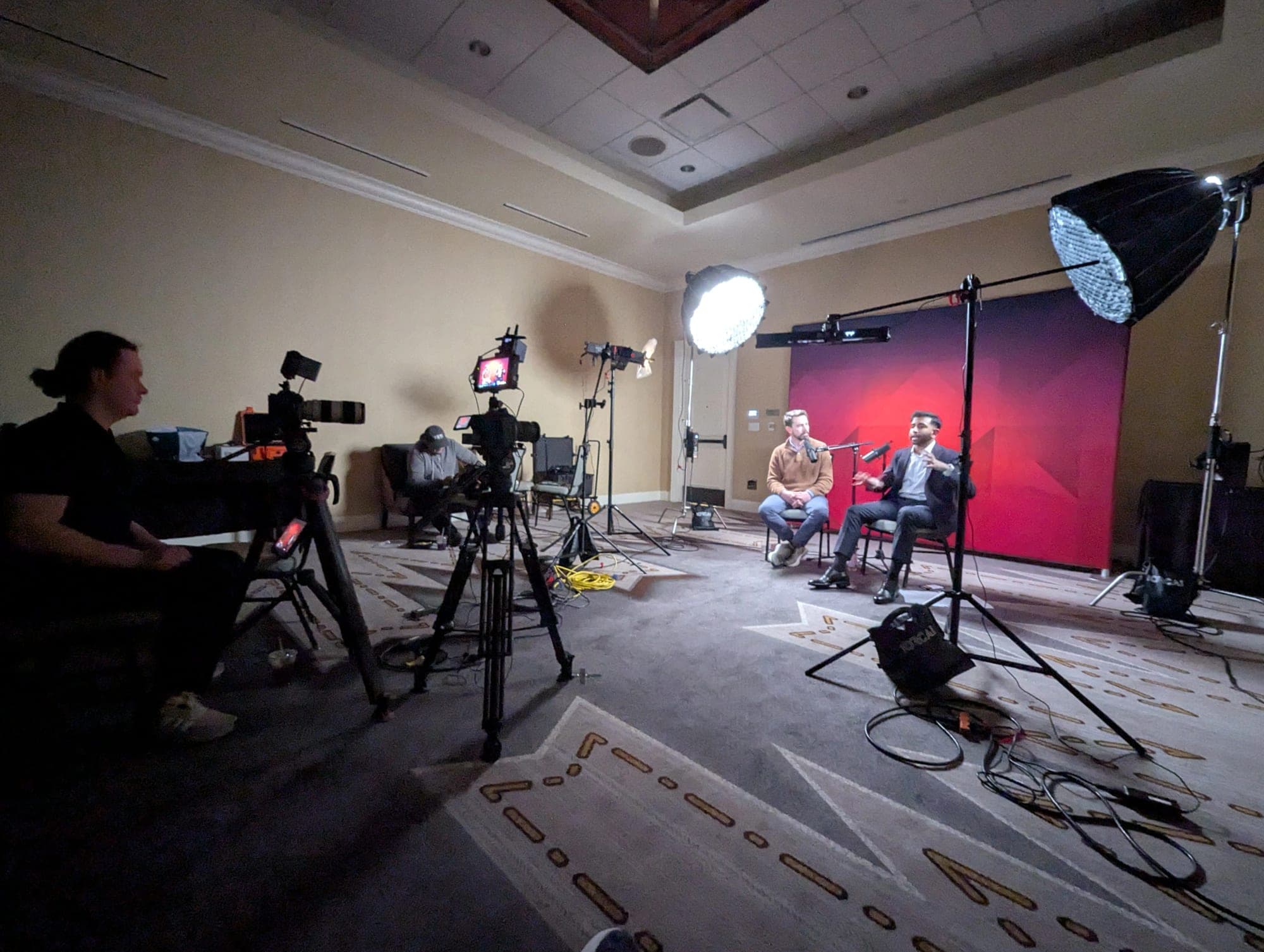 On-site video crew filming an interview on a pink backdrop